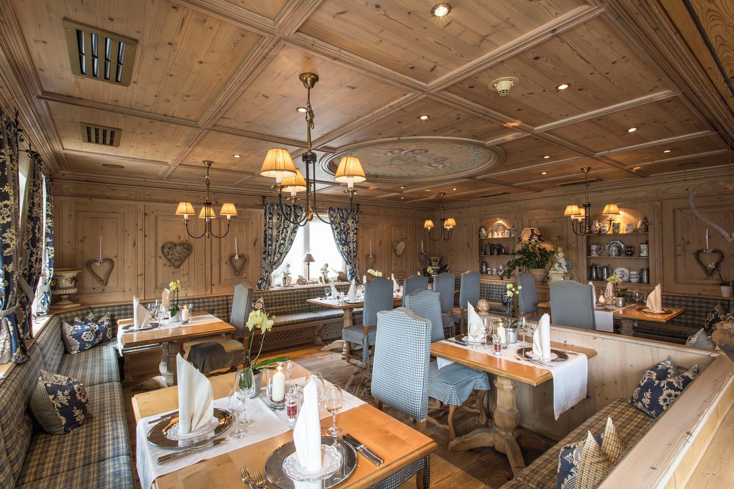 Un restaurant avec des boiseries, des sièges à motifs à carreaux et des lustres.