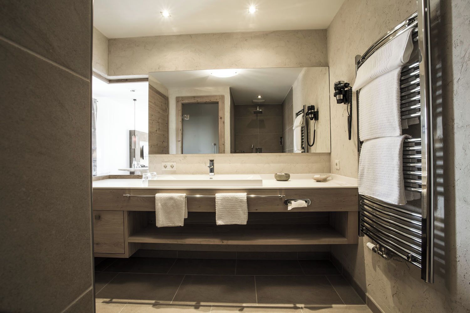 Un baño moderno con un espejo grande, un lavabo con toallero y un calentador de toallas.