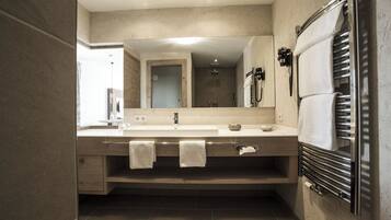 Un baño moderno con un espejo grande, un lavabo con toallero y un calentador de toallas.