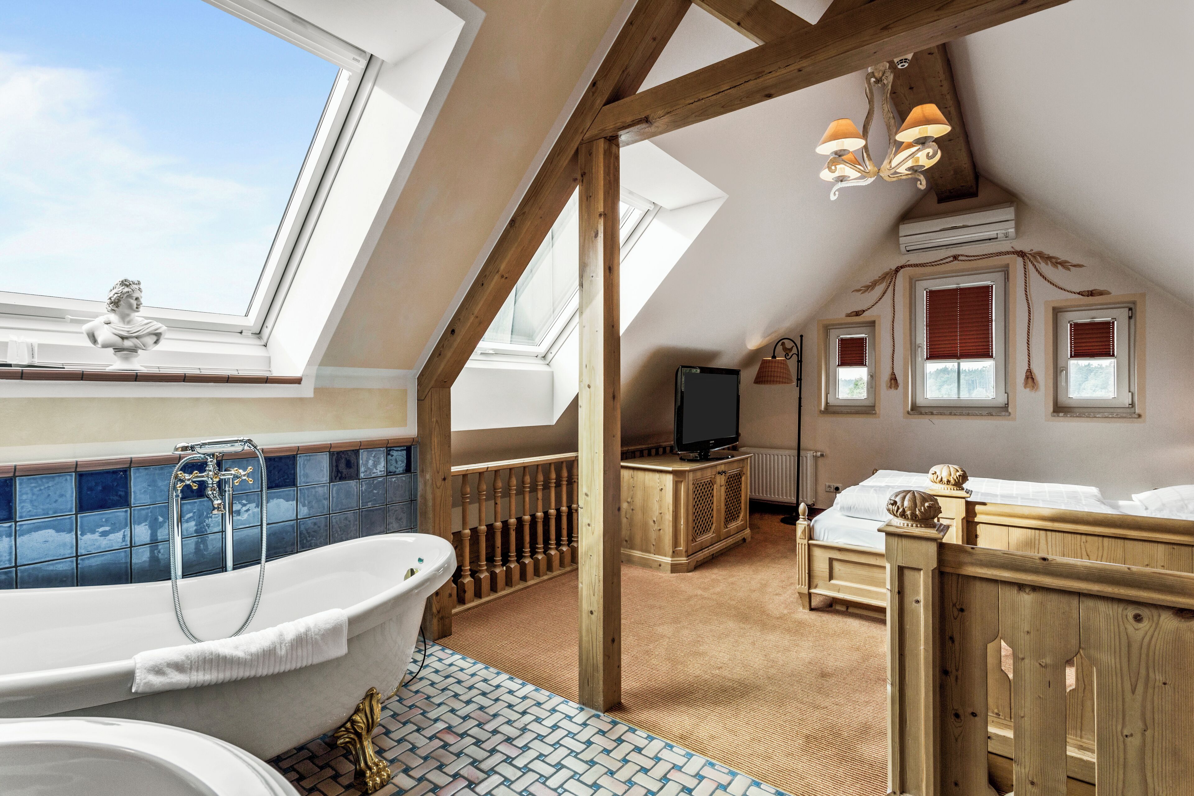 Ein Zimmer mit hohen Decken, einem Oberlicht, einer freistehenden Badewanne, einem hölzernen Bett und einem Fernseher auf einer Holzkommode.