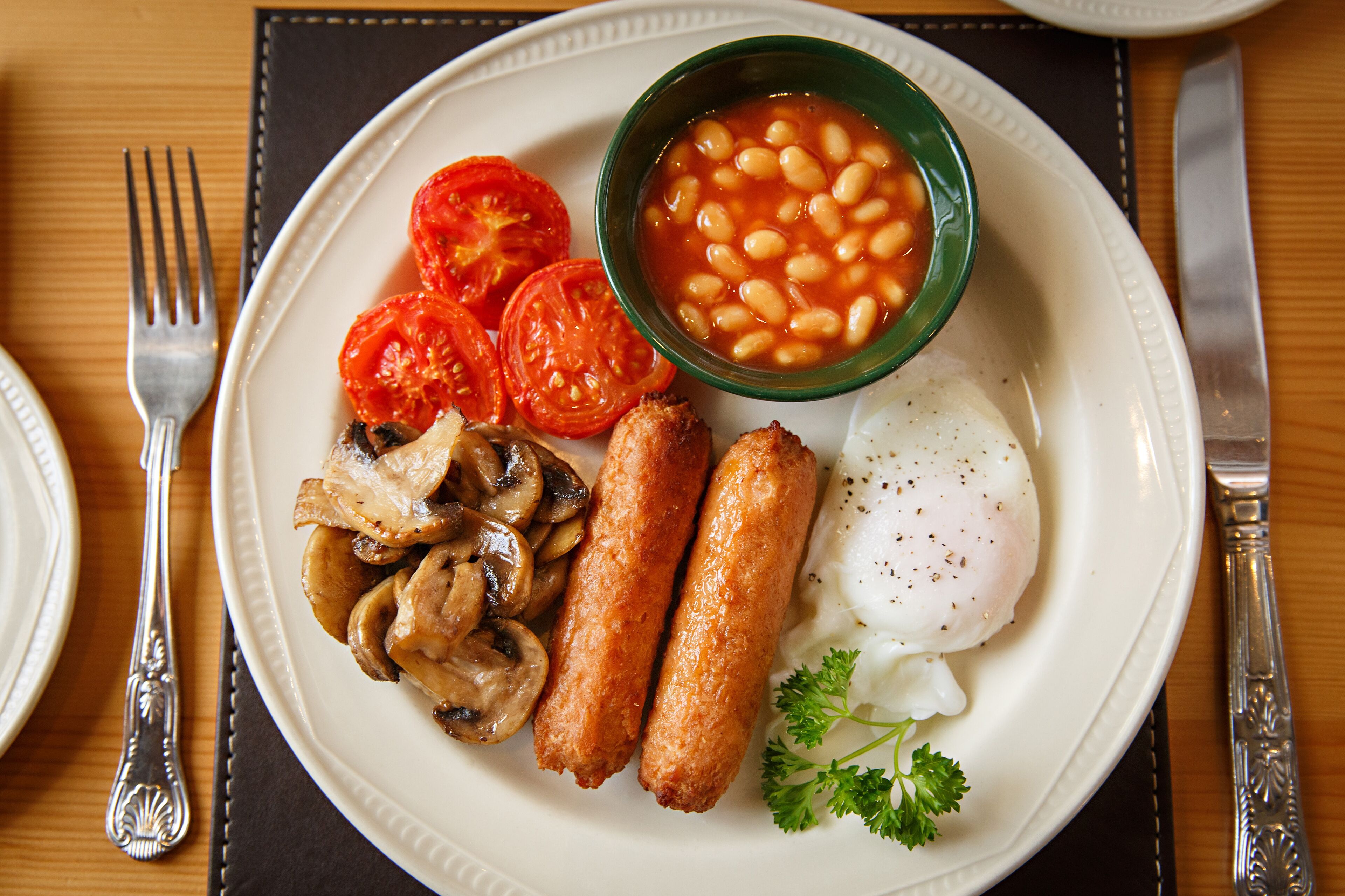 Un plato con huevos, champiñones, salchichas, tomates y frijoles.