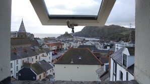 A view from a window overlooking a coastal town with buildings and a prominent church spire. - The Olive Branch (Ilfracombe)