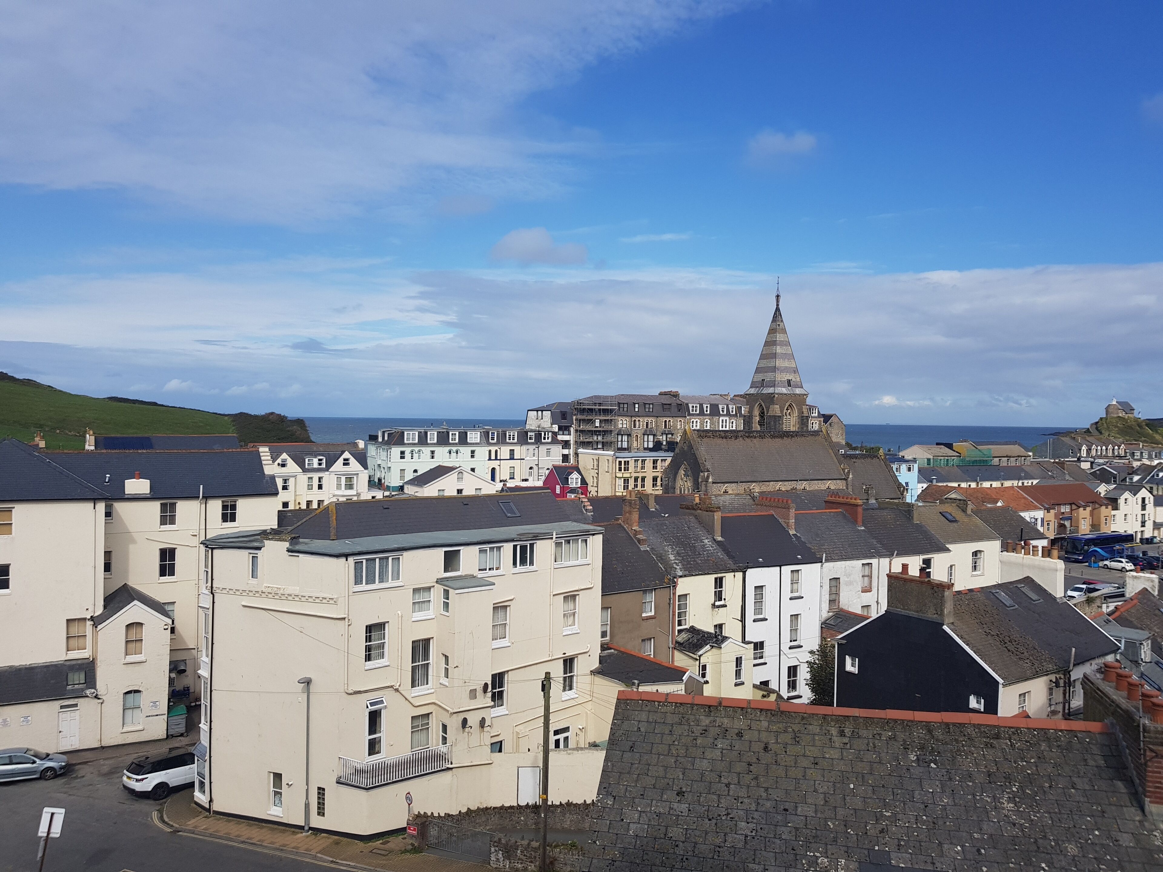 A coastal town with a prominent church steeple, residential buildings, and a clear view of the sea.