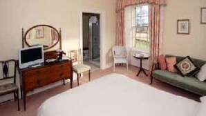 Une chambre à coucher comprenant un lit, une commode, une chaise, une petite table et un téléviseur.