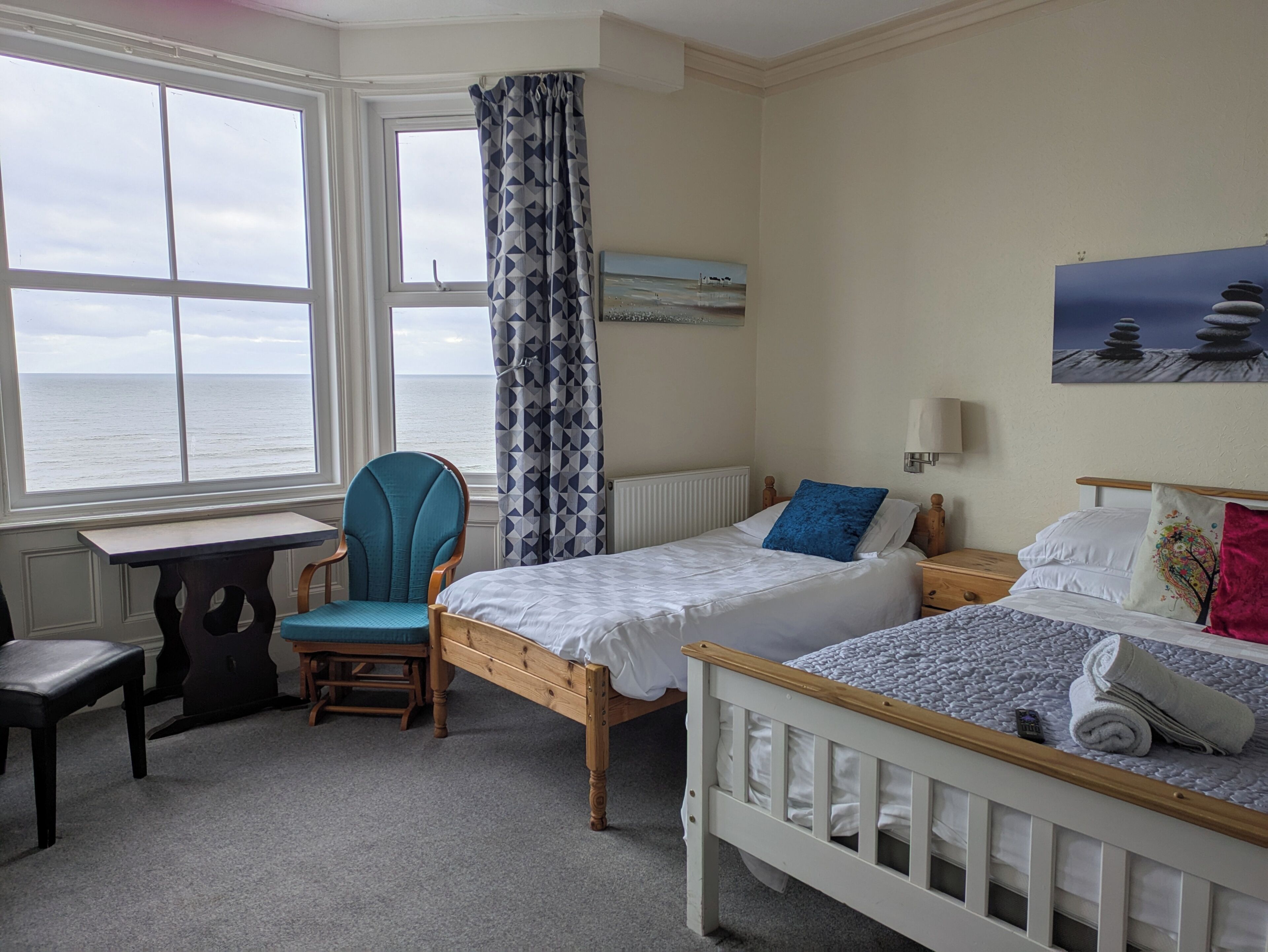 Ein Schlafzimmer mit Bett, Stuhl, Tisch und Meerblick.