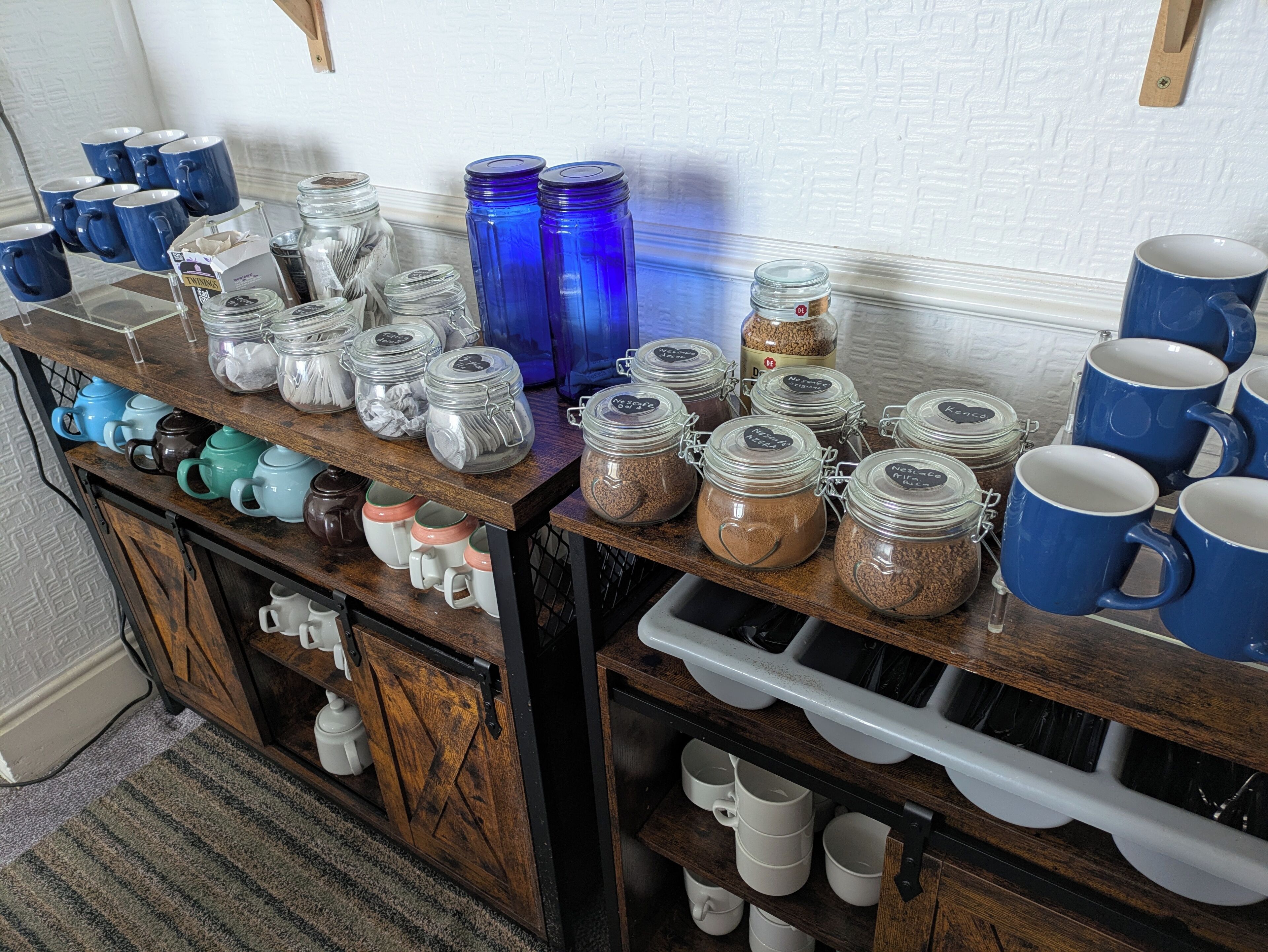 A kitchen counter with various mugs, teapots, and storage jars.