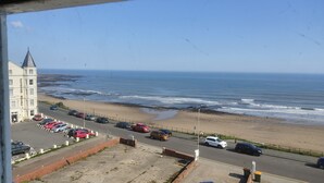 A coastal view with a building, a parking lot, and the ocean. - The Kenton (Scarborough)