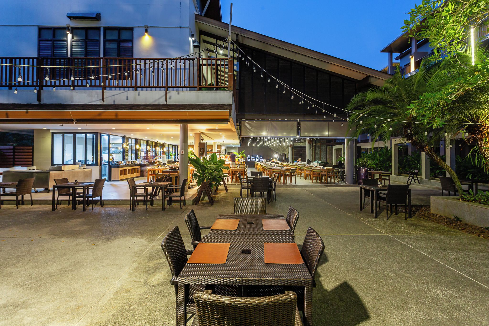 An outdoor dining area with tables and chairs, a bar area, and a view of the building's exterior.