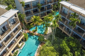 A multi-story hotel with a central swimming pool surrounded by palm trees and balconies. - Deevana Plaza Krabi (Krabi)