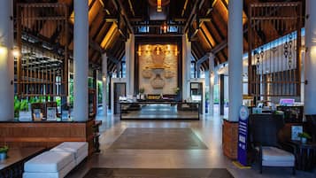 A spacious lobby with a reception desk, seating areas, and a decorative wall with a clock.