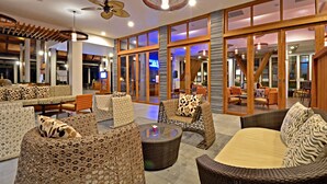 A spacious indoor area with wicker furniture, large windows, and a ceiling fan. - Deevana Plaza Krabi (Krabi)
