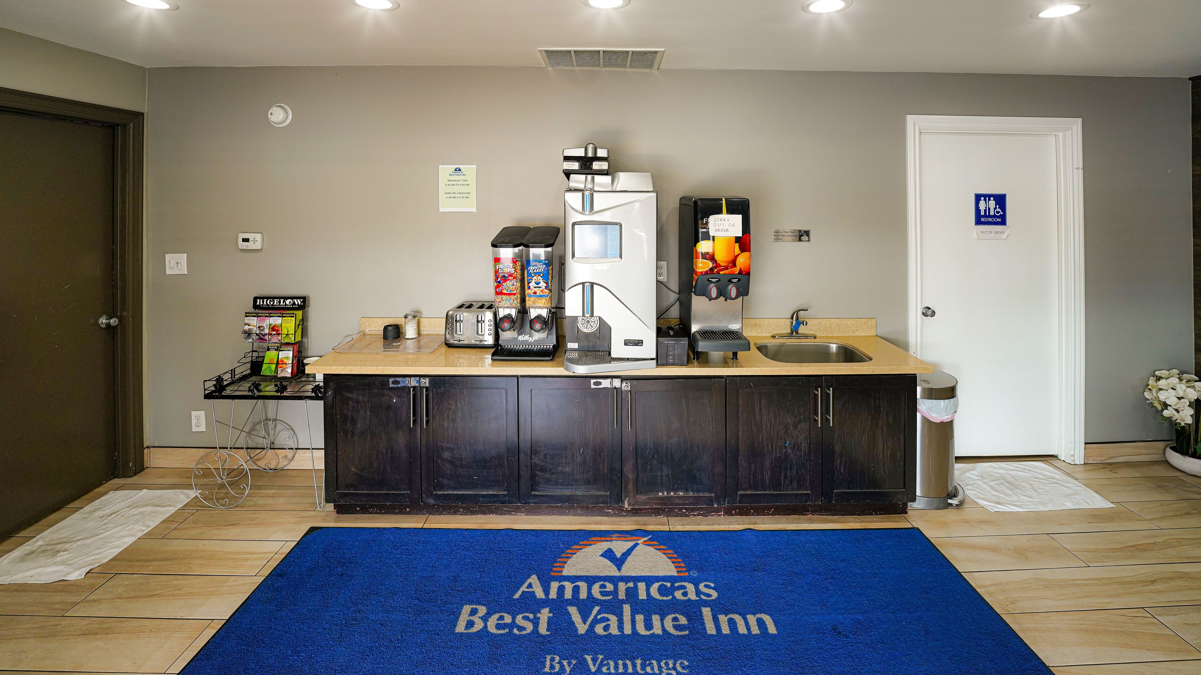 A kitchenette area with a coffee maker, toaster, and a refrigerator. There is a sign indicating the hours of operation for the kitchen.