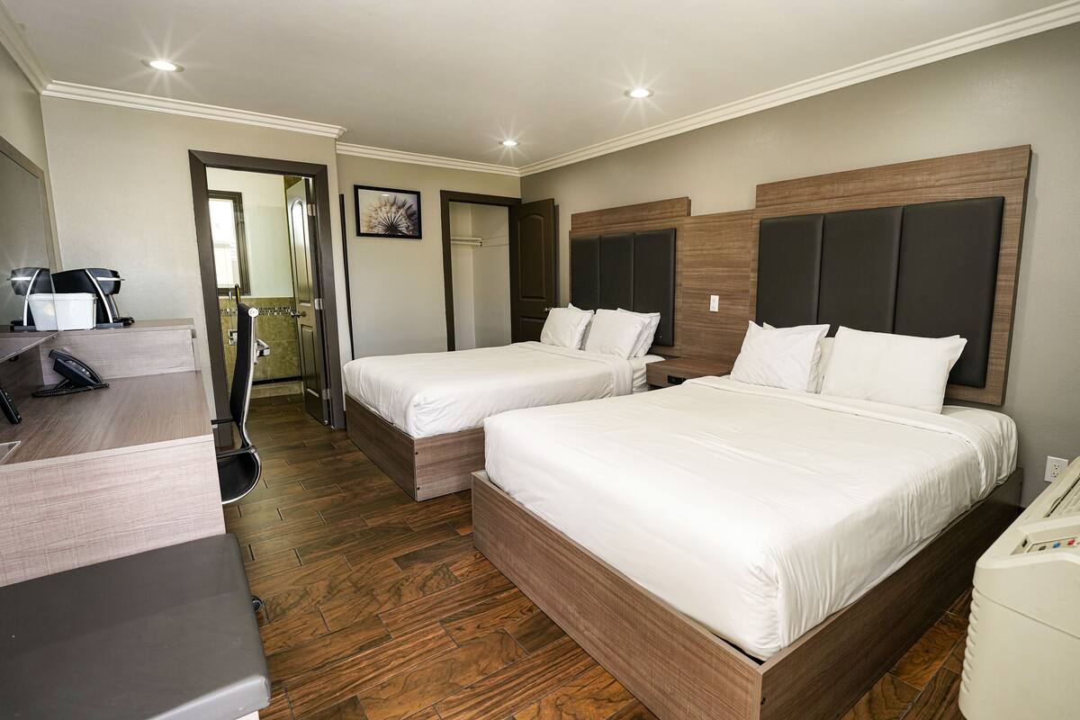Une chambre d’hôtel avec deux lits, un bureau avec un téléphone et un miroir.