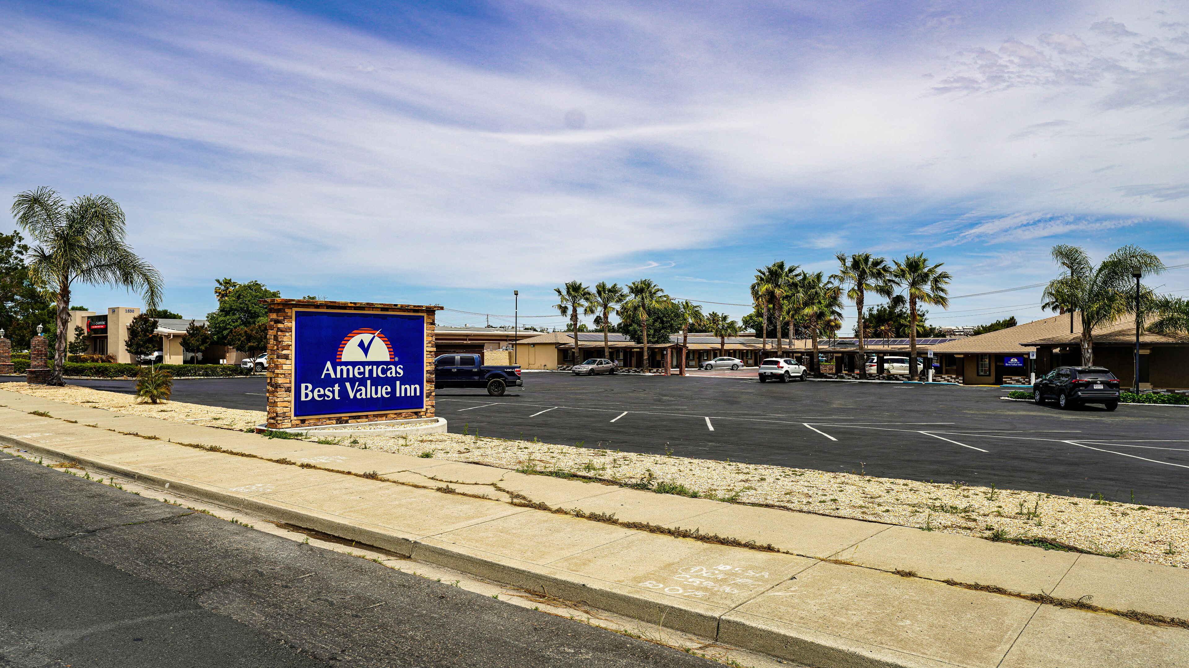A Best Value Inn sign, a parking lot, and a row of palm trees.