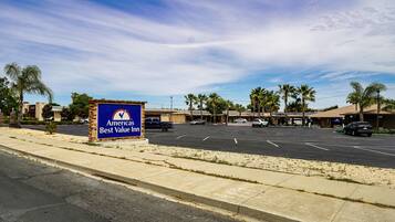 A Best Value Inn sign, a parking lot, and a row of palm trees.