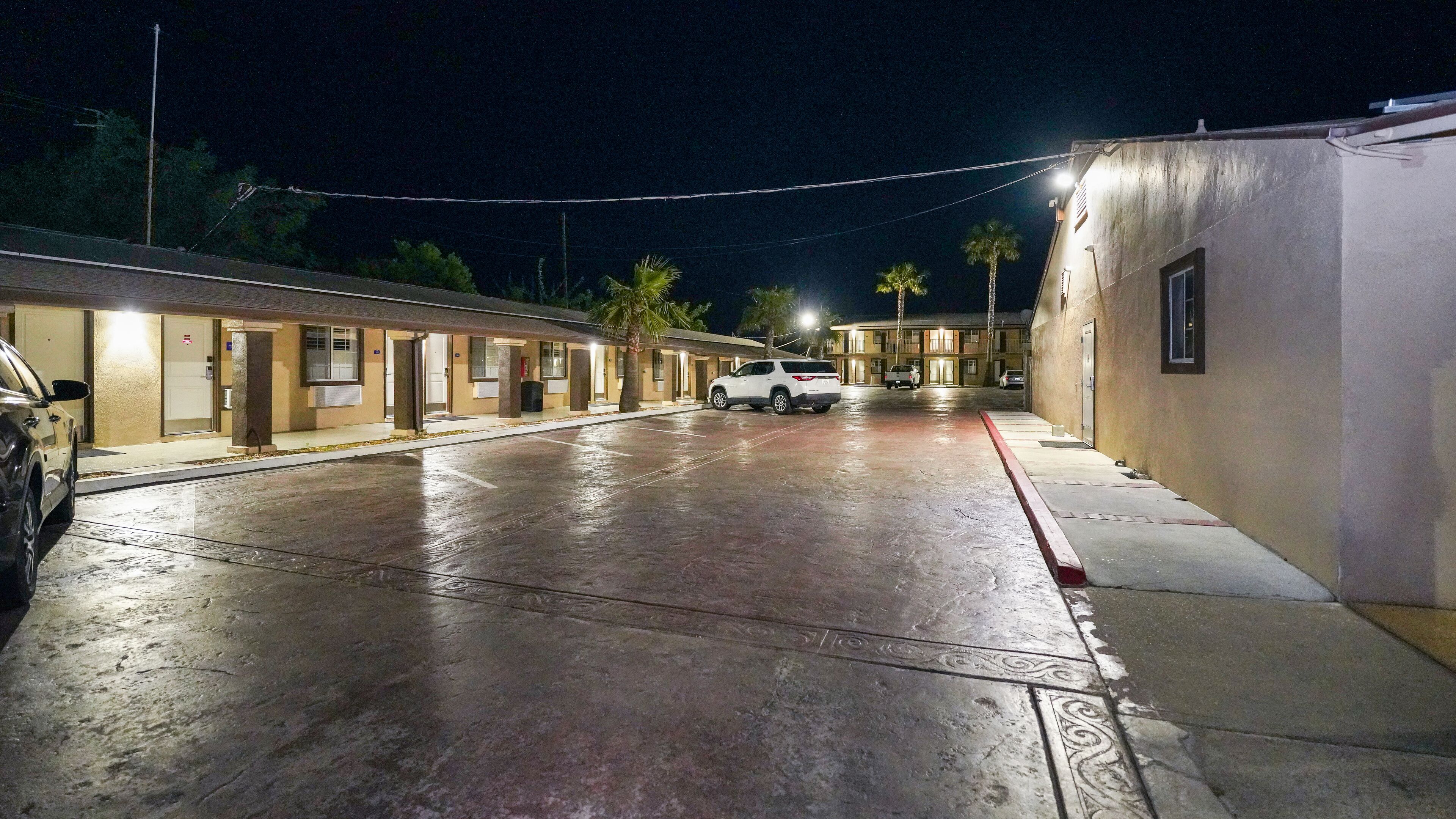 A motel with a parking lot, multiple rooms, and a small building on the right.