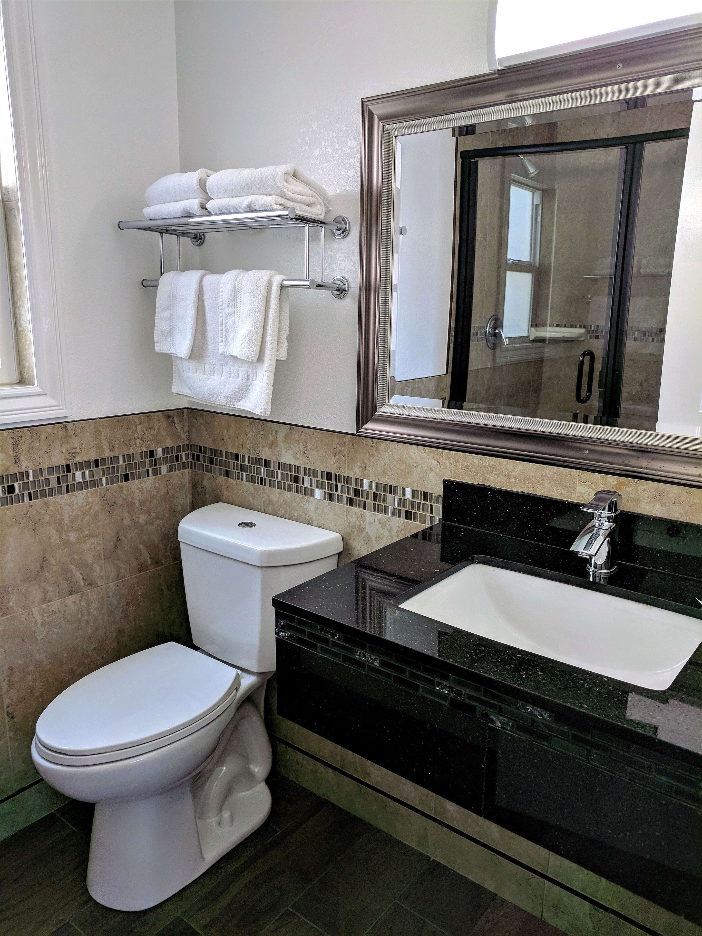 A modern bathroom with a toilet, sink, and a large mirror.