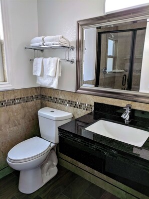 Moderni kylpyhuone, jossa on wc, pesuallas ja suuri peili.