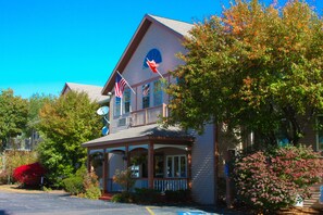 A two-story house with a porch, American flags, and a satellite dish.