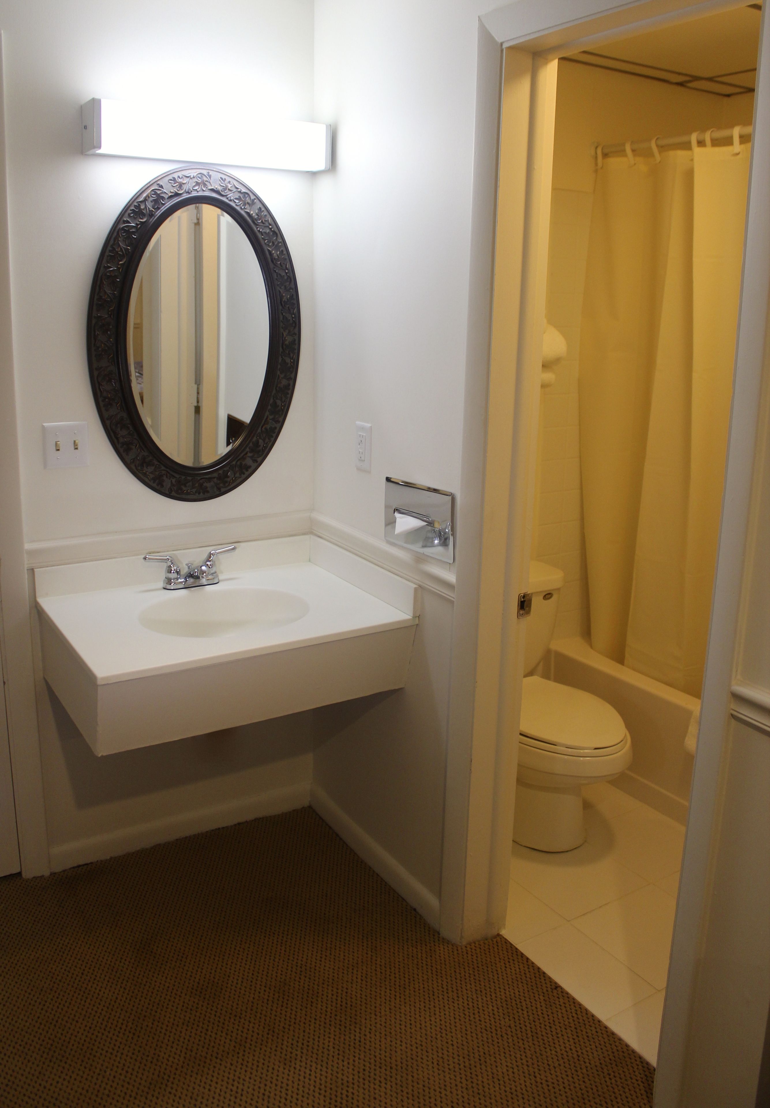 A bathroom with a white sink, a mirror, and a toilet.