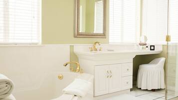 A bathroom with a bathtub, a vanity with a mirror, and a toilet.
