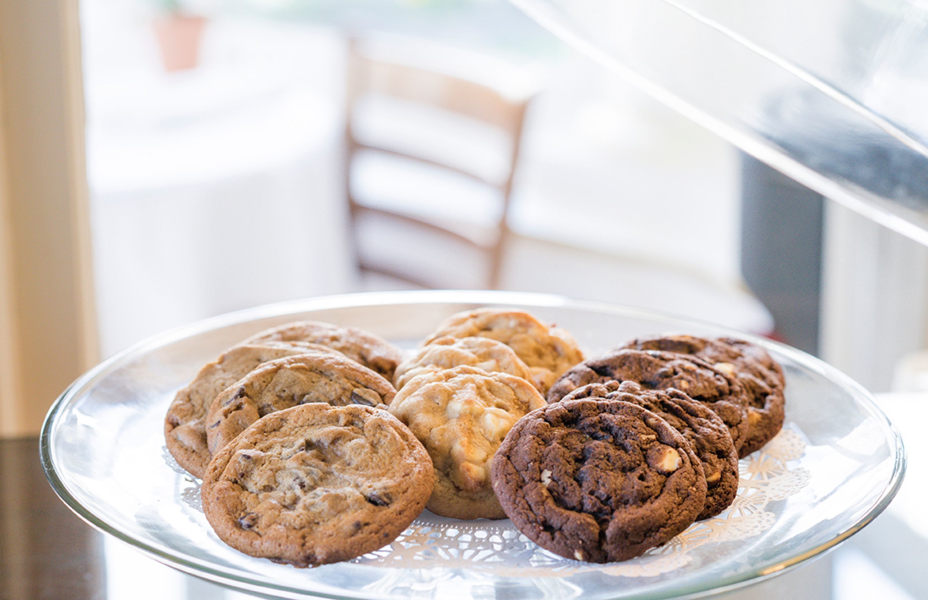 Une assiette en verre contenant divers types de biscuits, posée sur une table.