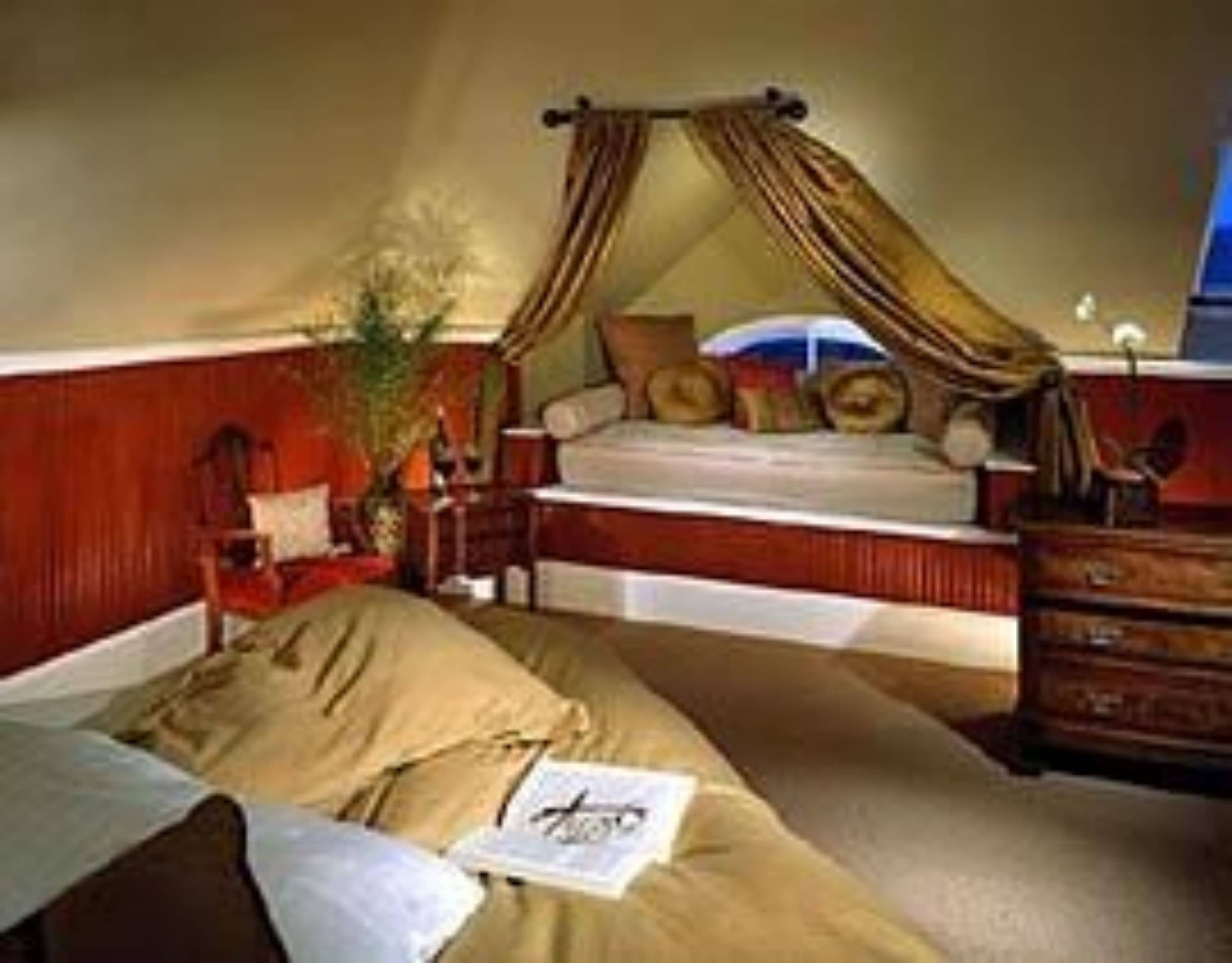 A bedroom with a bed, a nightstand, a dresser, and a window with curtains.