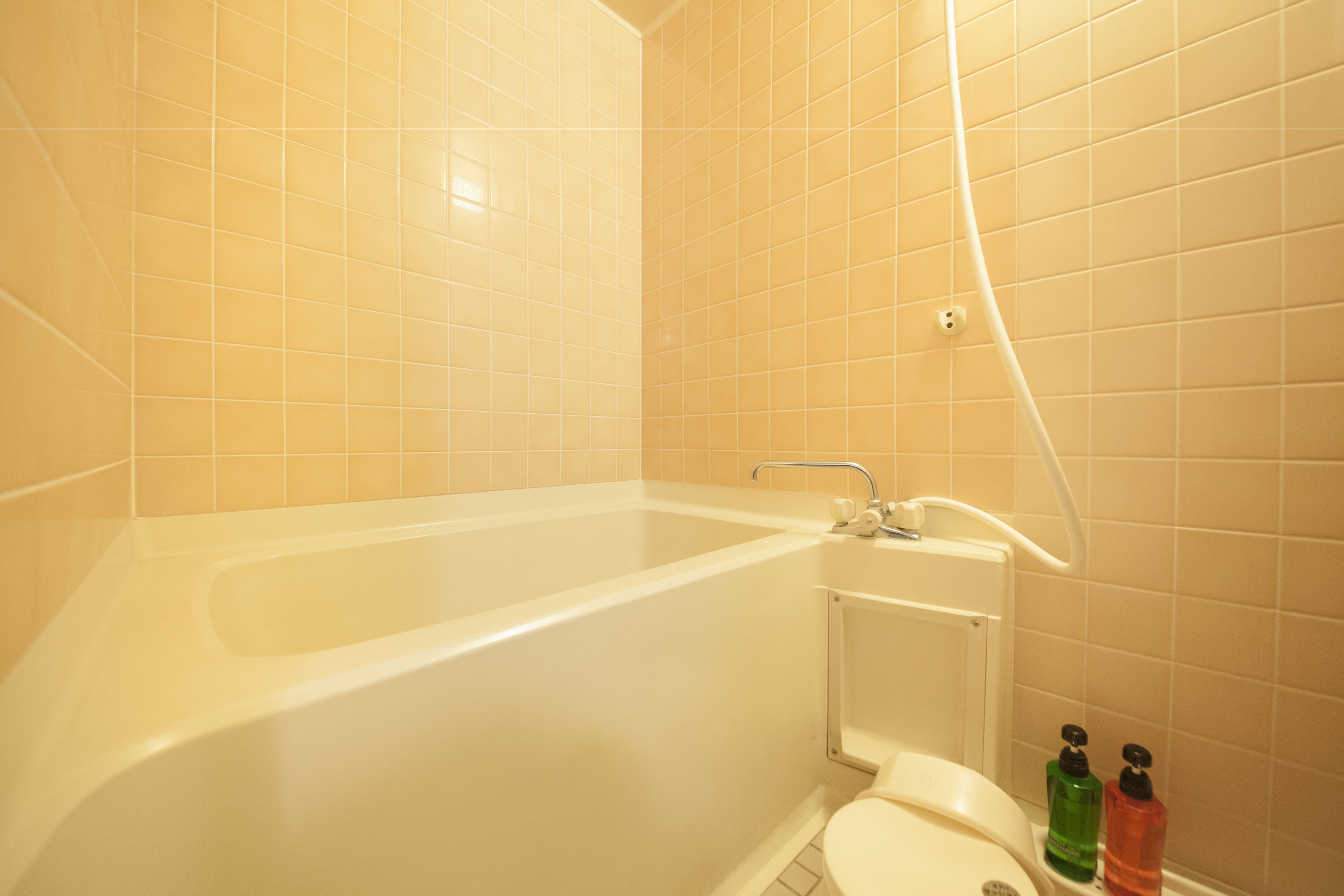 A bathroom with a bathtub, toilet, and two hand soap dispensers.