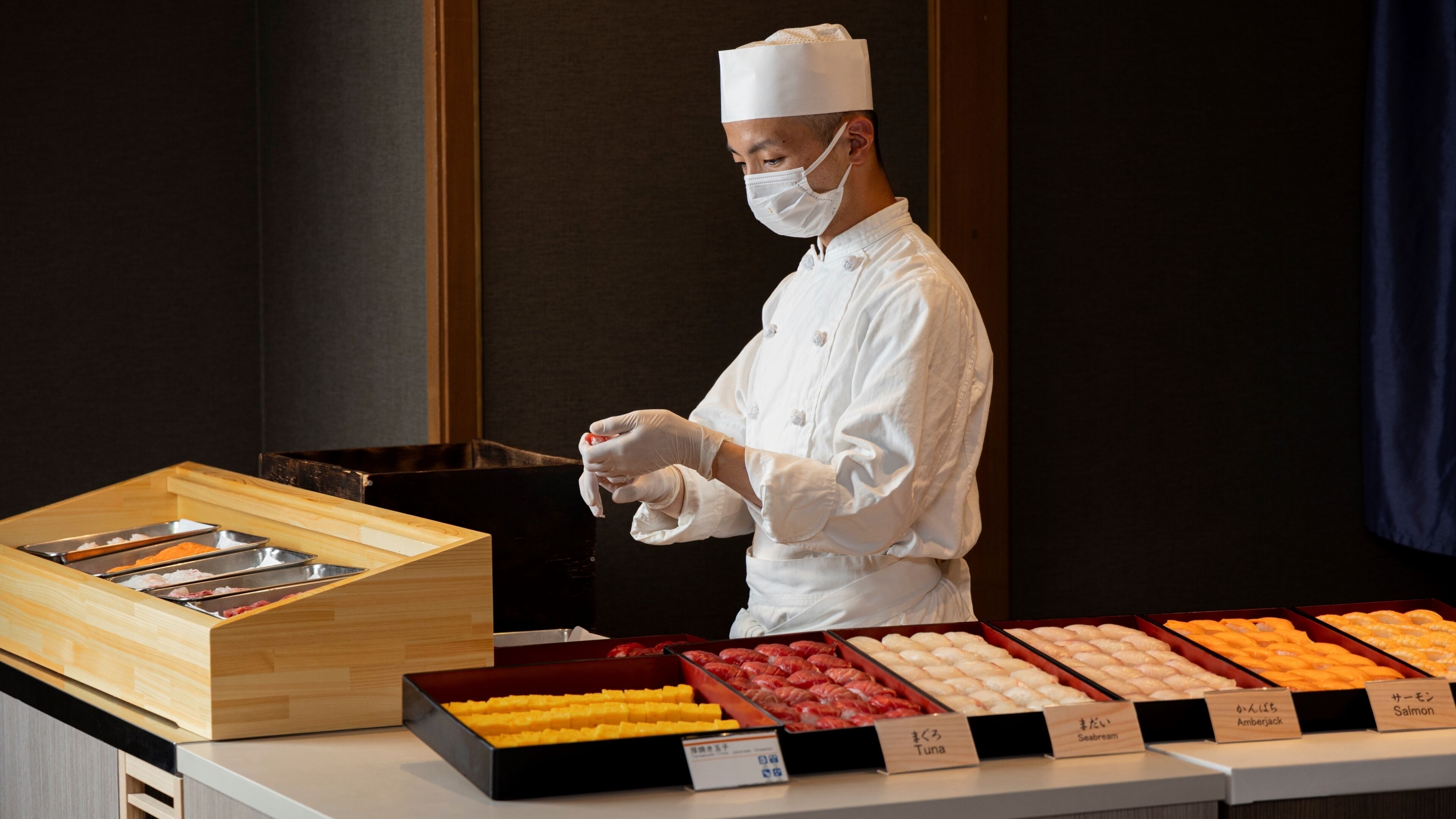 A chef in a white uniform preparing food at a buffet with various seafood options.