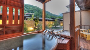 A wooden deck with a hot tub, wooden railings, and a view of a mountainous landscape. - Hotel Okada (Hakone)