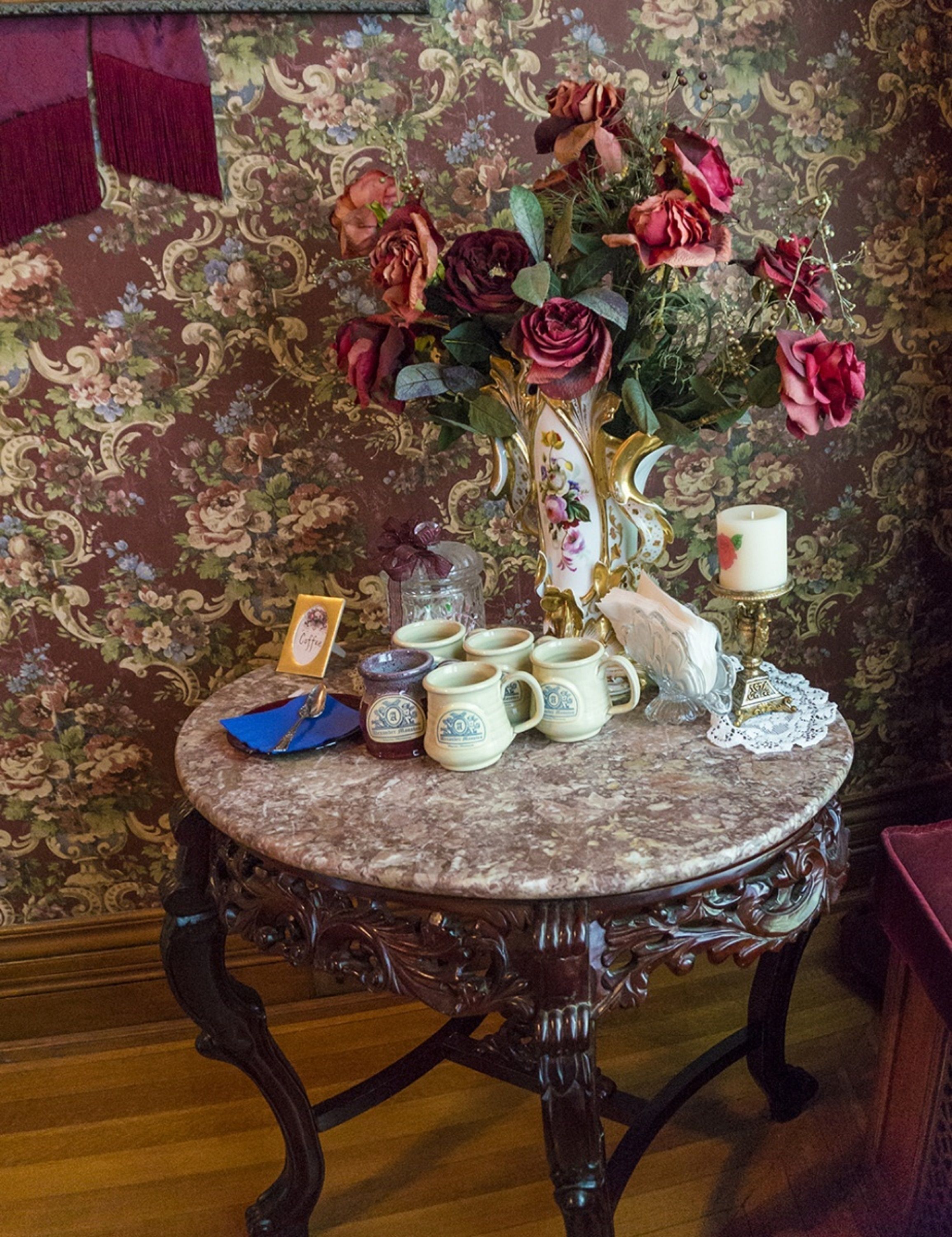 Een tafel met een bloemstuk, een kaars en verschillende keramische mokken.