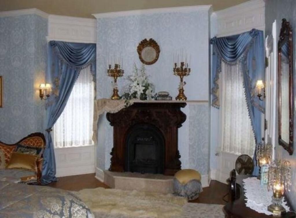 A room with a fireplace, a bed, and a mirror.