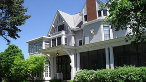 A large, two-story house with a prominent front porch, large windows, and a brick chimney. - Alexander Mansion Bed and Breakfast (Winona)