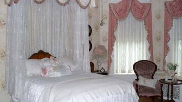 Un dormitorio con cama a dosel, una silla y una mesita.
