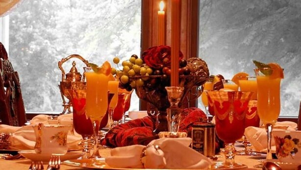 A table set for a meal with various dishes, glasses of orange juice, and a vase with flowers. - Alexander Mansion Bed and Breakfast (Winona)