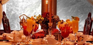 A table set for a meal with various dishes, glasses of orange juice, and a vase with flowers. - Alexander Mansion Bed and Breakfast (Winona)