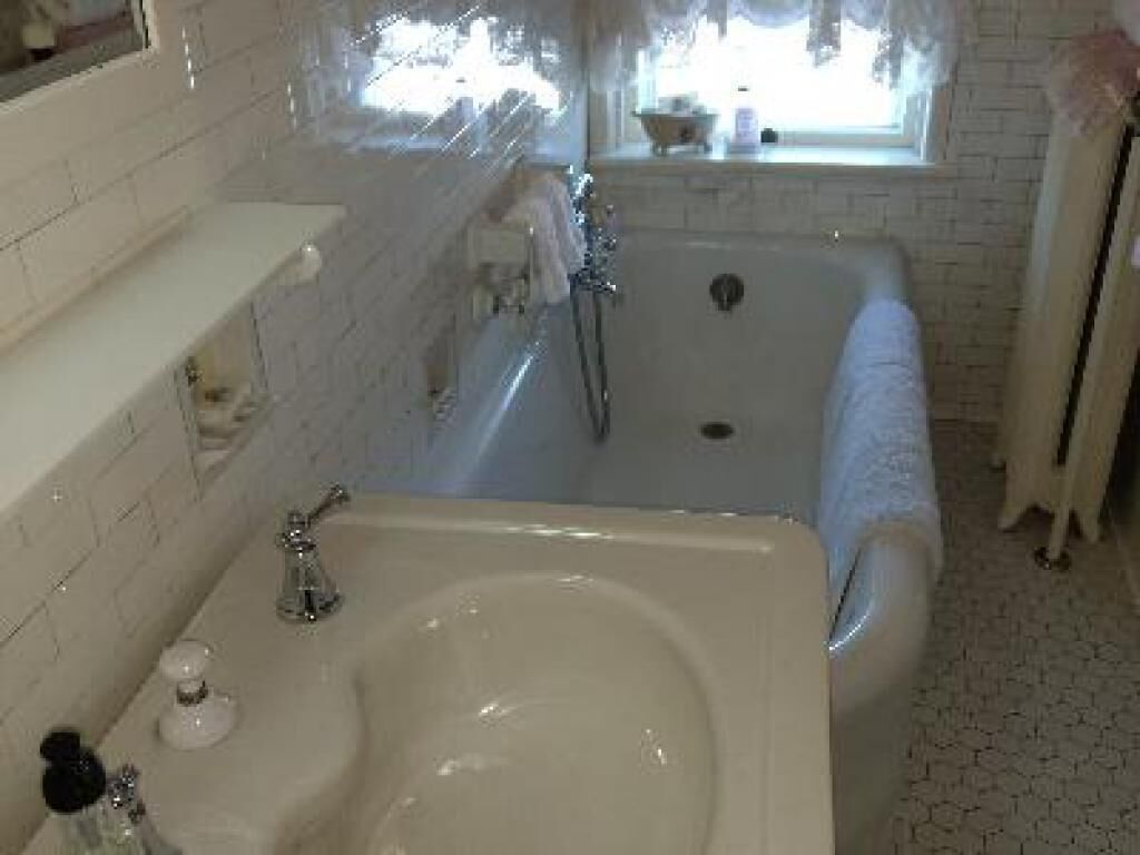 A bathroom with a bathtub, a sink, and a window.