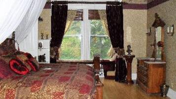 Une chambre à coucher avec un grand lit, une commode, un miroir et une fenêtre avec des rideaux.