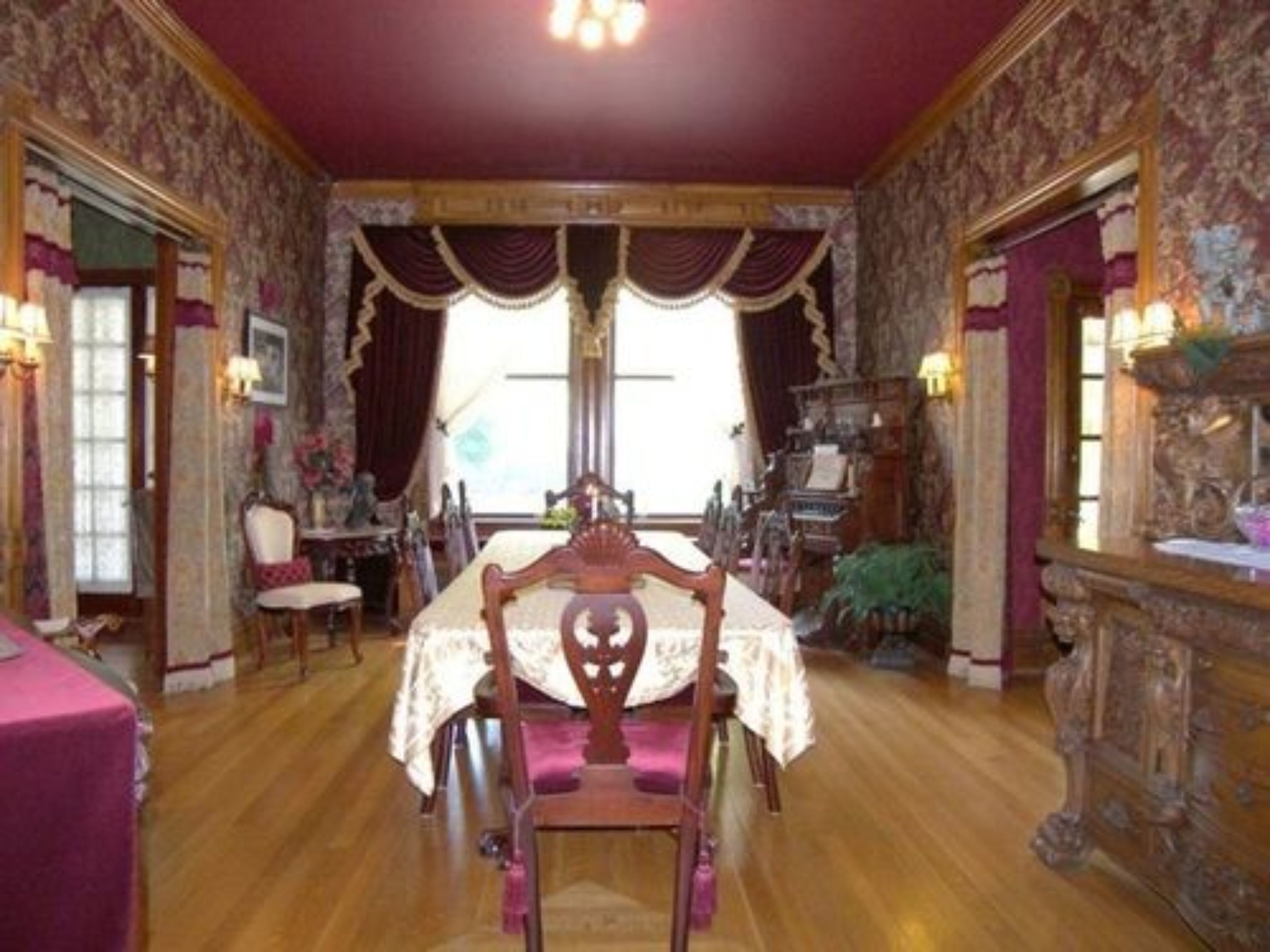 Une salle à manger avec une table et des chaises en bois, un papier peint décoratif et un lustre.