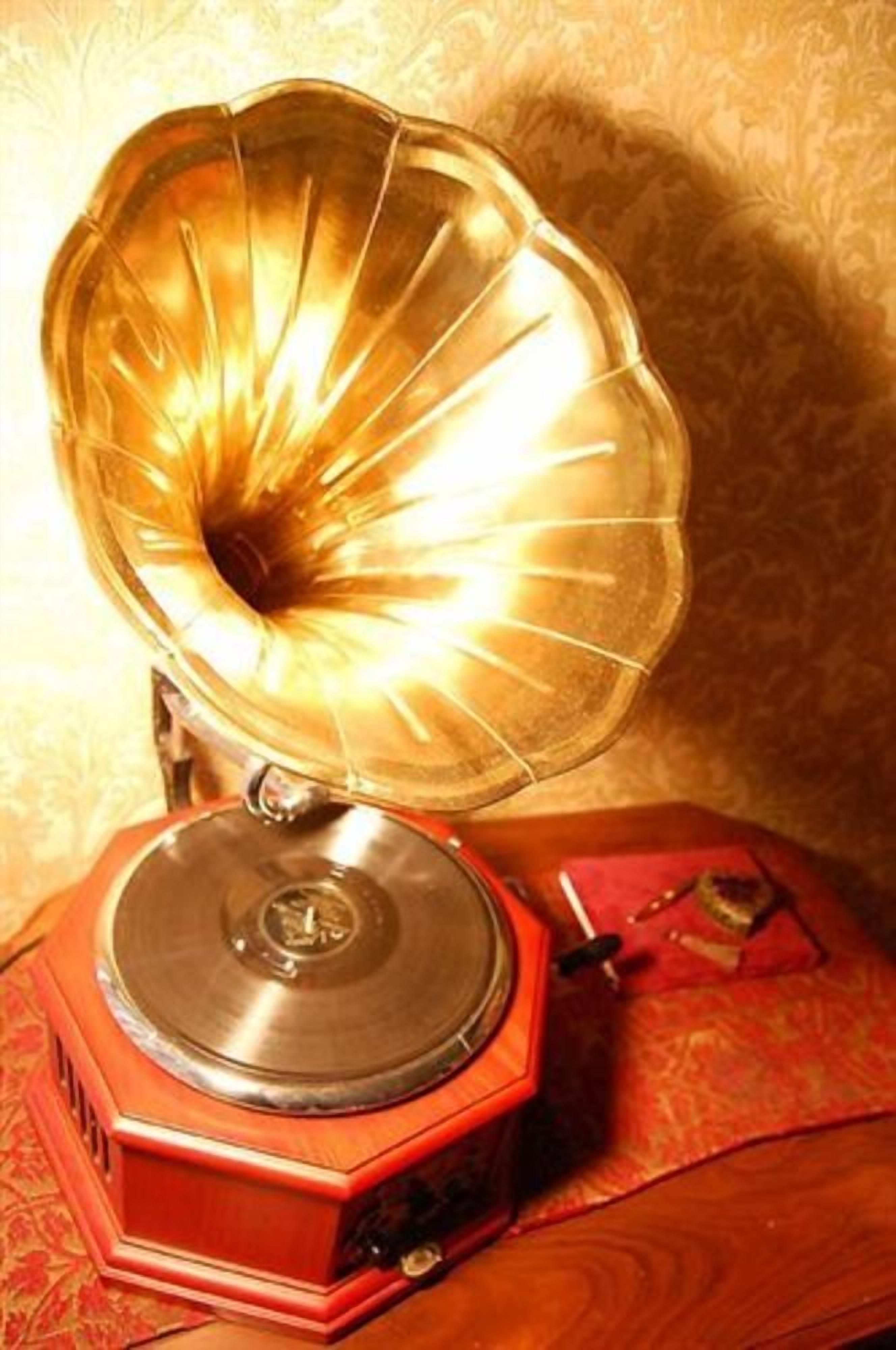 Un gramophone ancien, doté d’une grande trompe et d’un socle rouge, posé sur une surface à motifs.