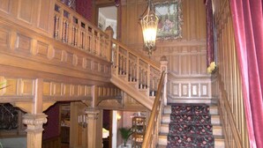 A grand staircase with a floral carpet, wooden balustrades, and a chandelier. - Alexander Mansion Bed and Breakfast (Winona)