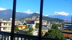 A view of a town with buildings and snow-capped mountains in the background. - Hotel Grand Holiday (Pokhara)