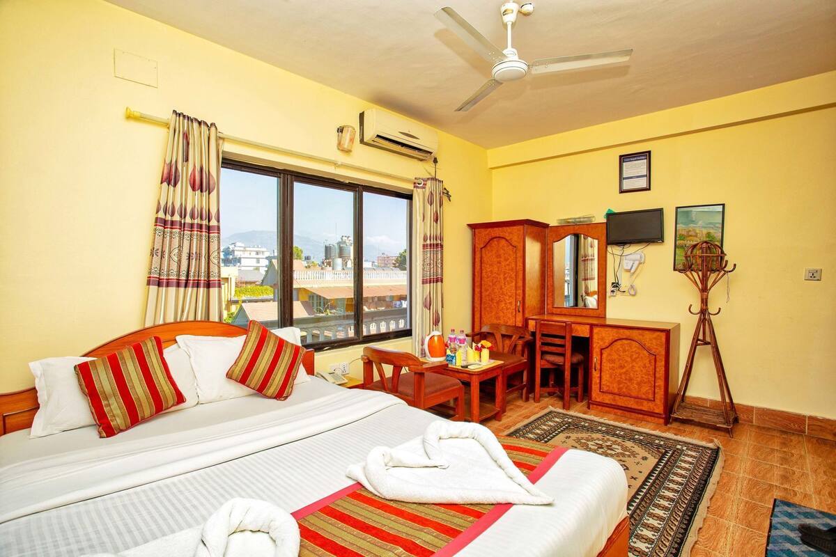 A hotel room with a bed, a desk, a chair, a television, and a window with a view.