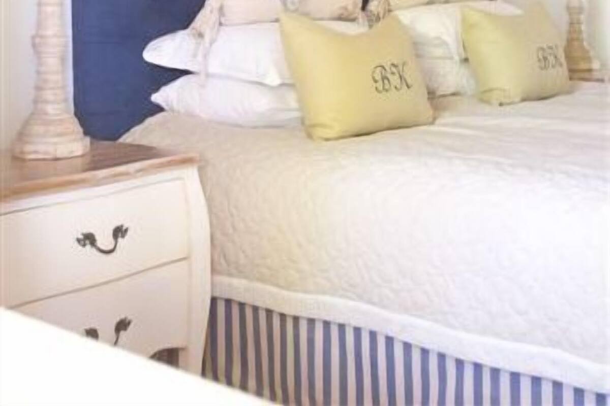 Un dormitorio con una cama grande, dos mesitas de noche y una lámpara de pared.