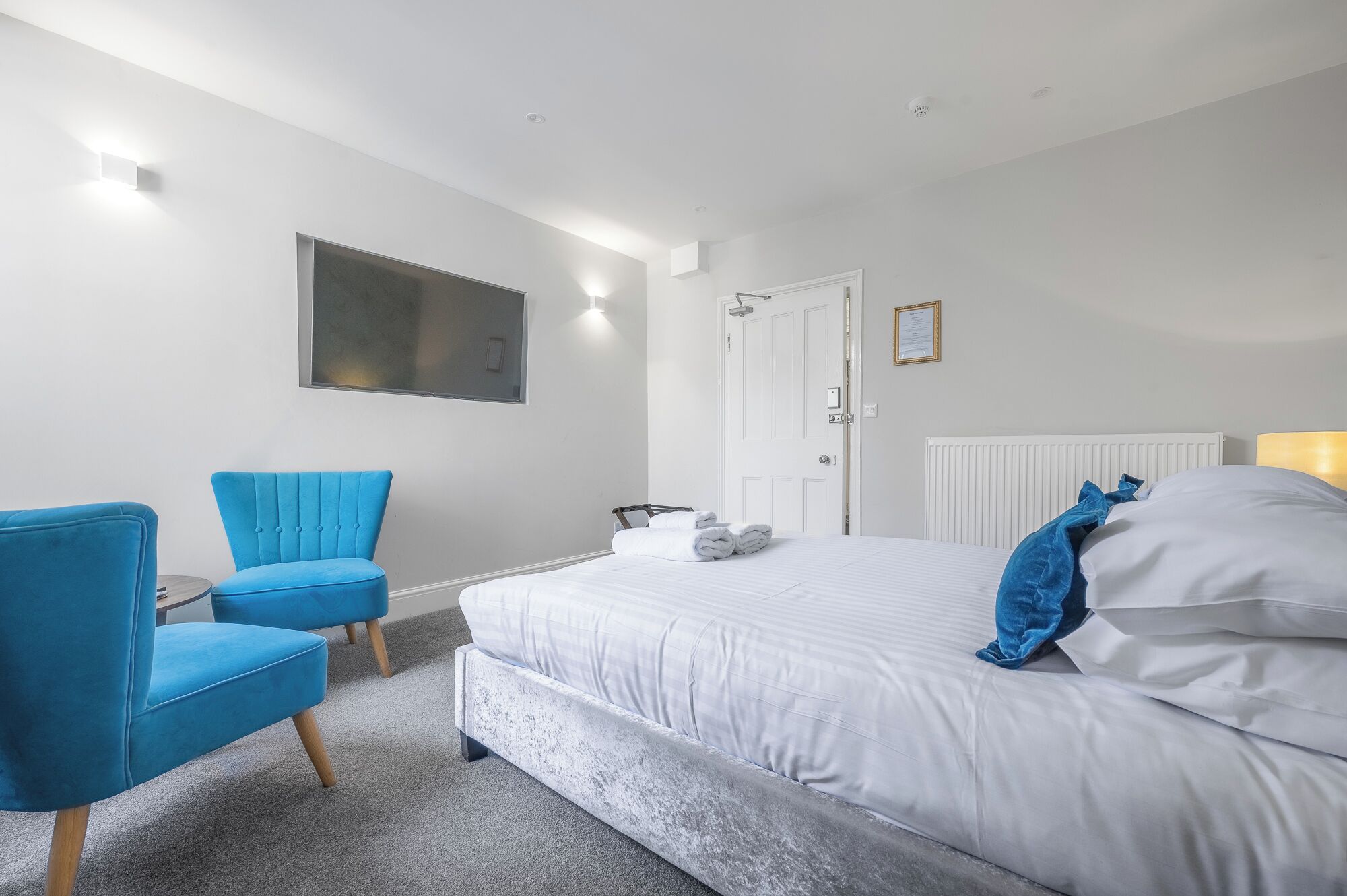 A modern bedroom with a large bed, a blue armchair, and a small table.
