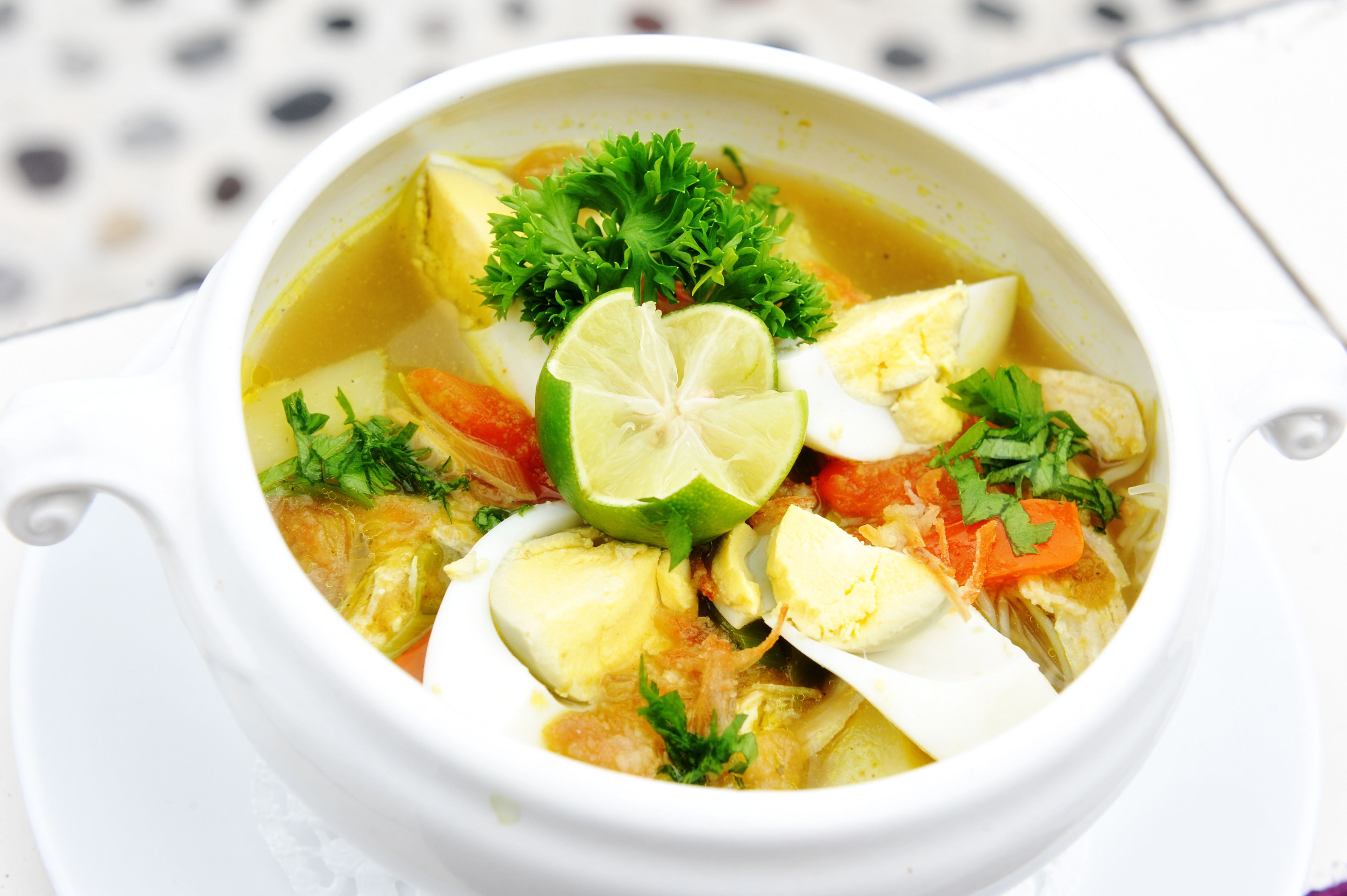 A bowl of soup with vegetables and herbs.