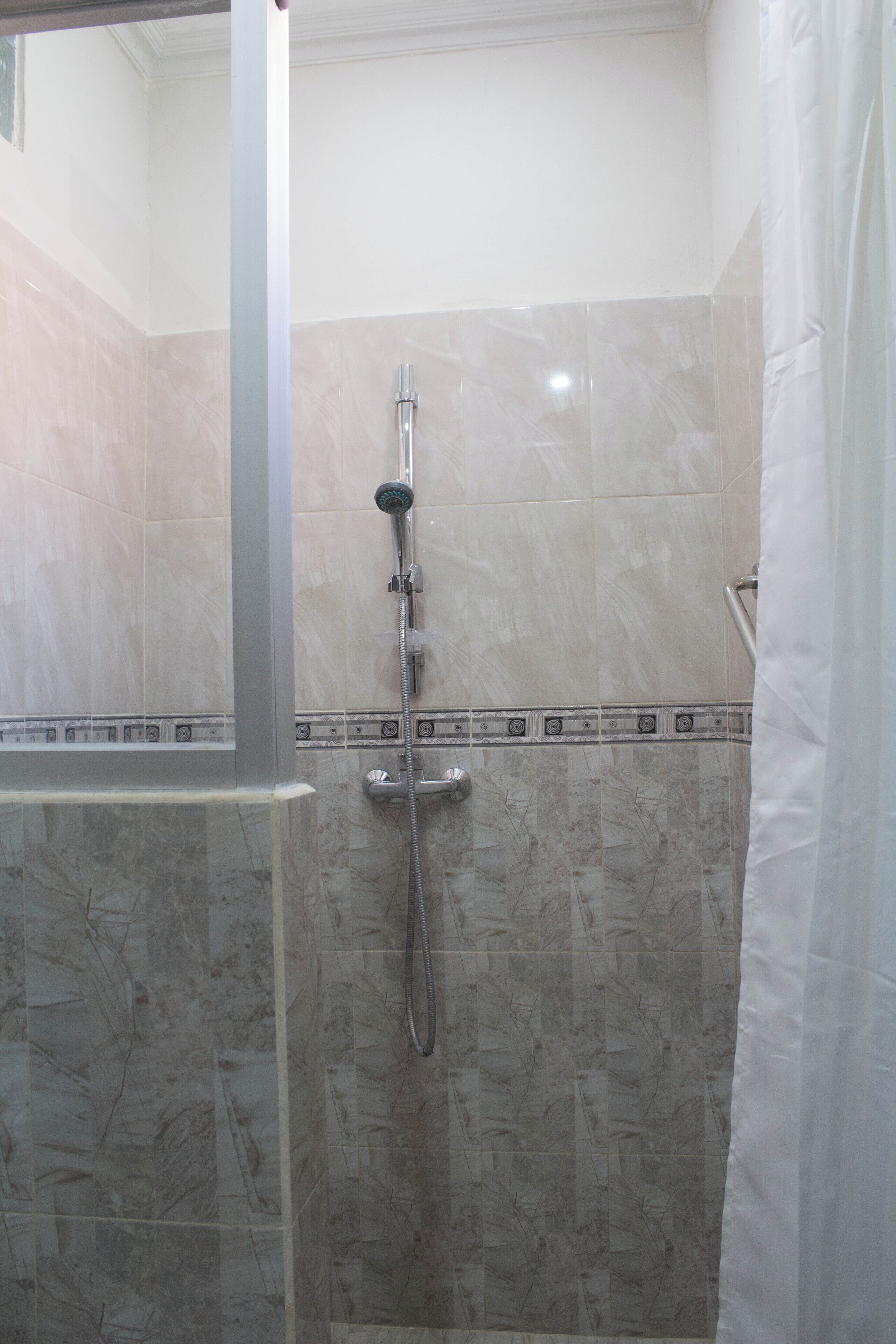 A bathroom with a shower, tiled walls, and a glass partition.