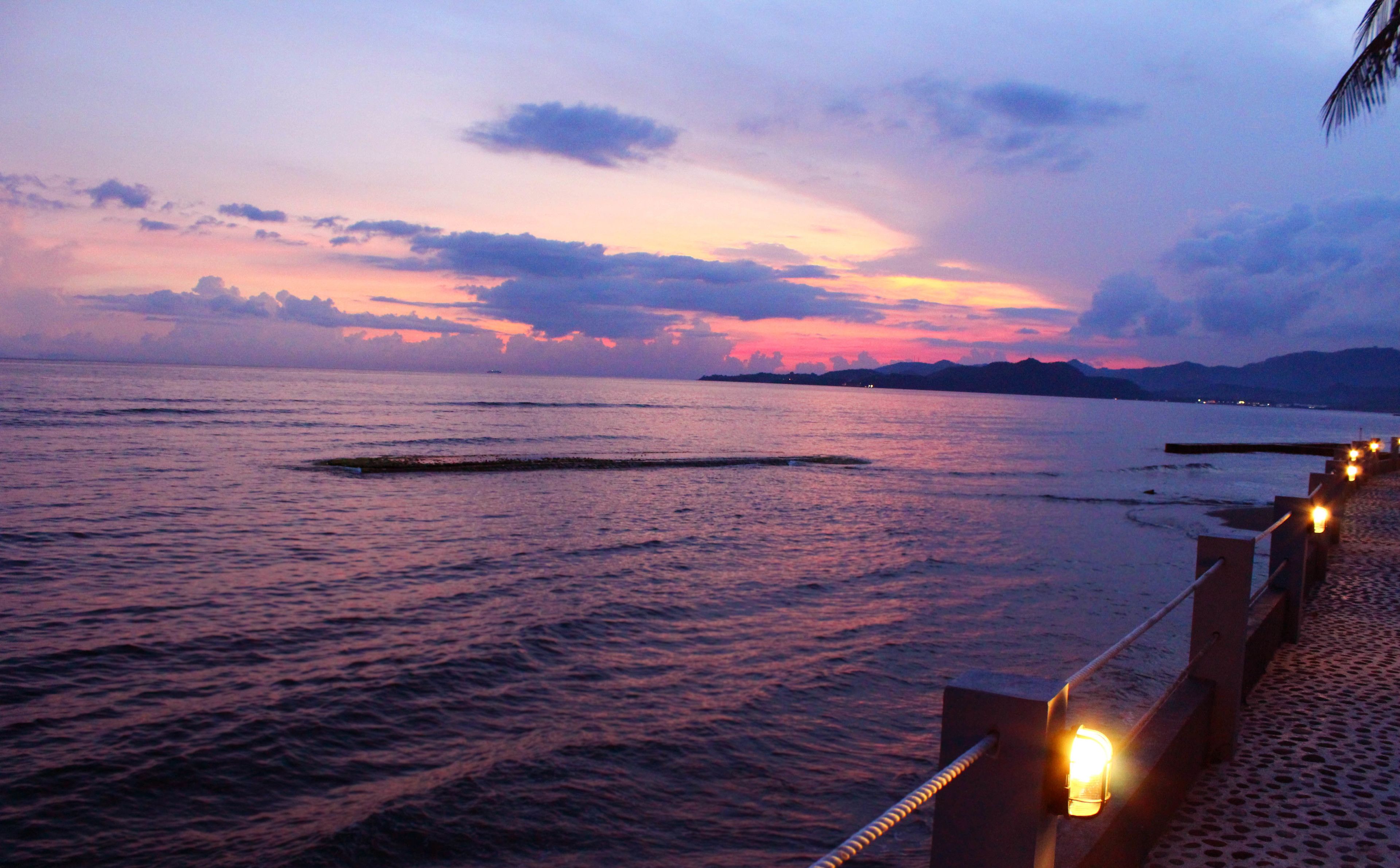 A coastal sunset with calm waters and a distant shoreline.