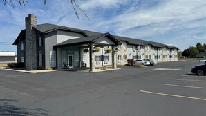 A motel with a stone facade, a covered front porch, and a parking lot. - The Woodridge Inn (Connersville)
