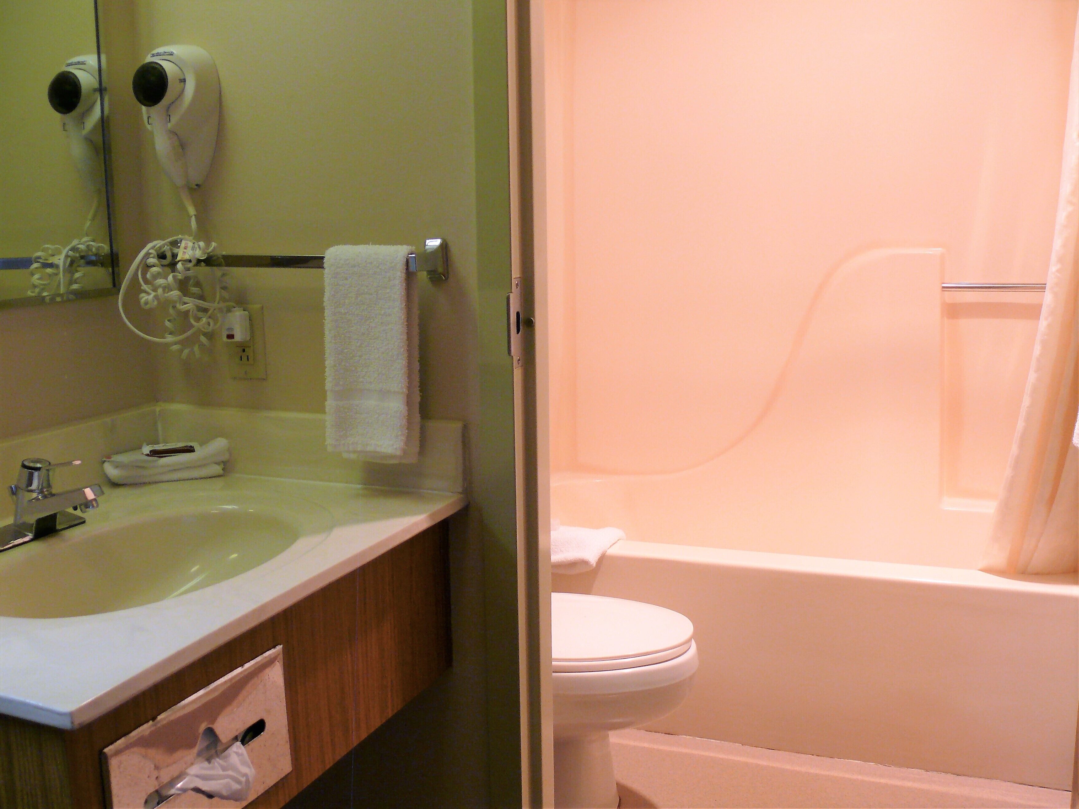 A bathroom with a sink, mirror, towel rack, and a bathtub.